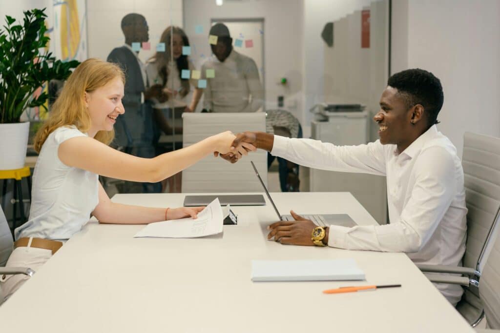 Free Business professionals completing a successful deal with a handshake in a modern office setting. Stock Photo